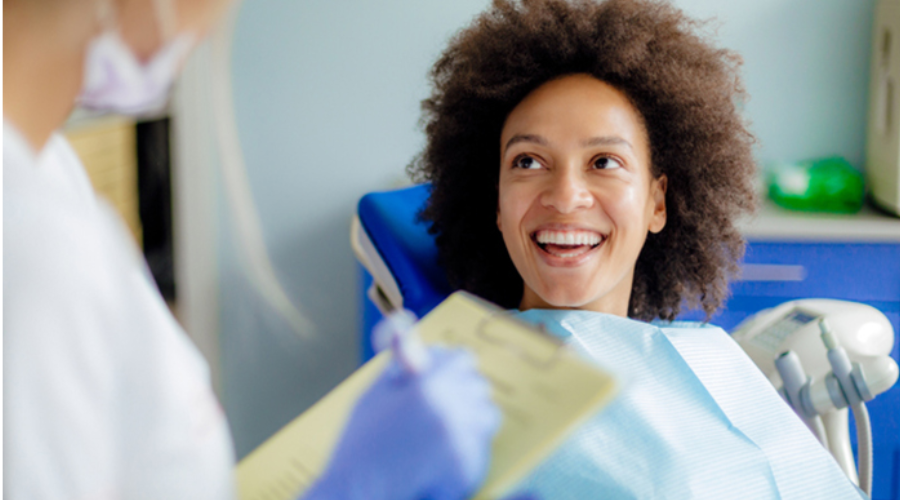 A smiling patient with an afro looks at a dental professional during a checkup.